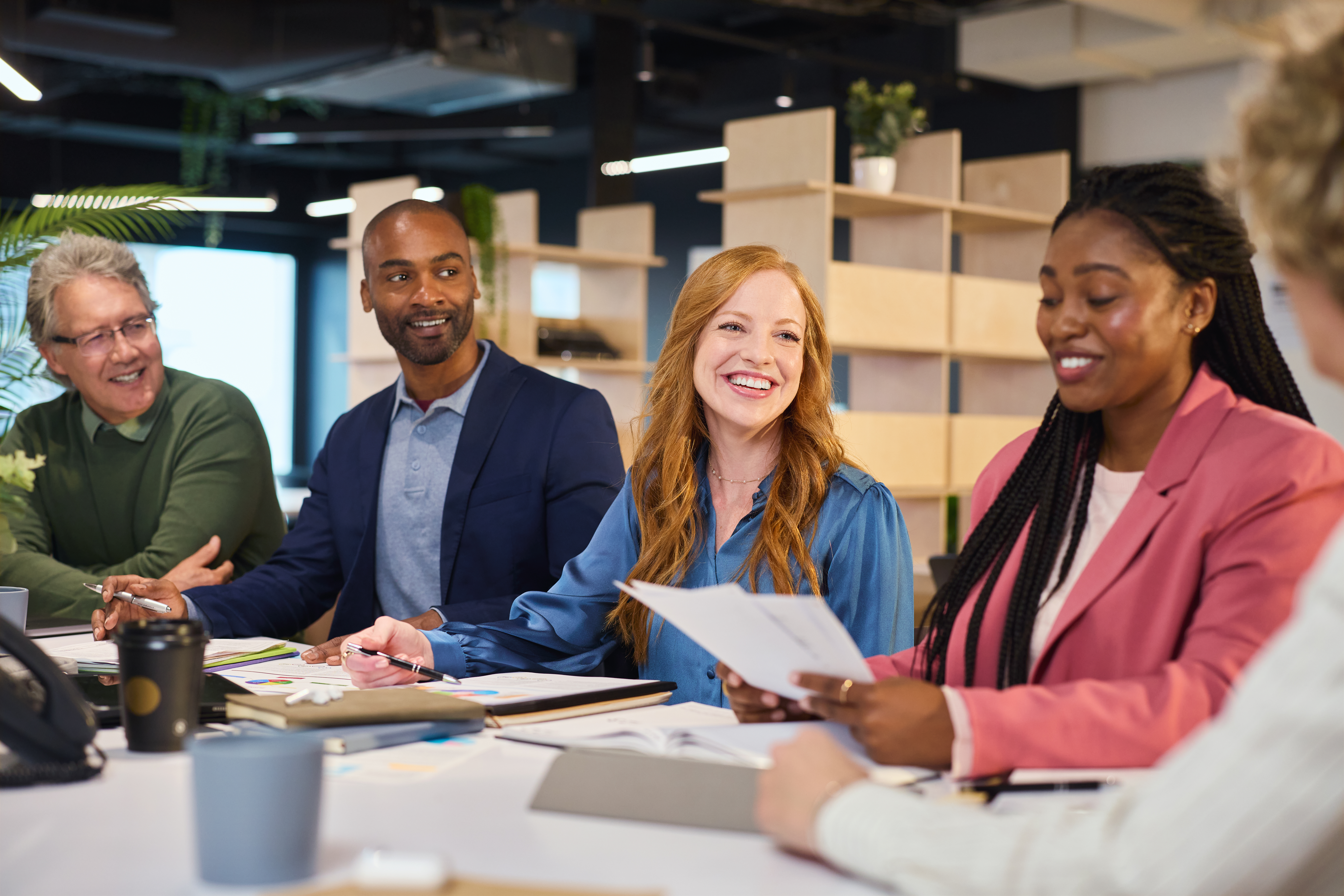 A group of professionals with good workplace skills gathers around a conference table.
