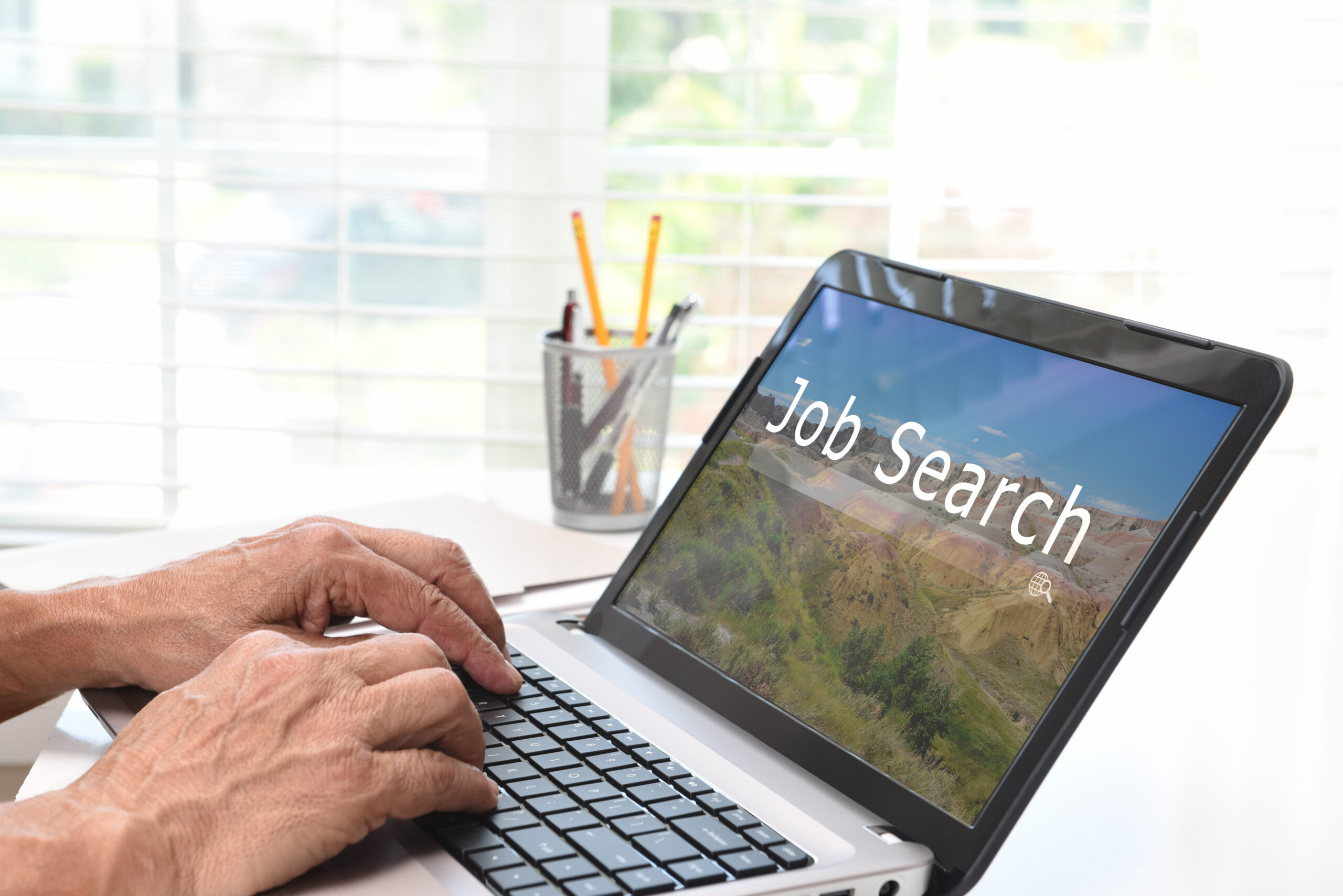 Man typing on a laptop, searching how to get hired fast.